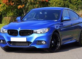 Modern blue luxury car parked by a scenic roadside on a sunny day. Stylish design.