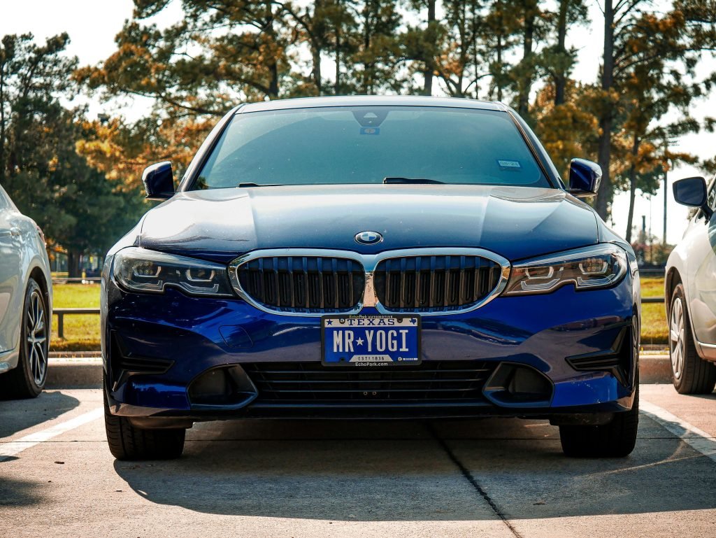Front view of a blue BMW 3 Series with a custom license plate in Arlington, Texas.