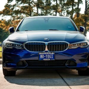 Front view of a blue BMW 3 Series with a custom license plate in Arlington, Texas.
